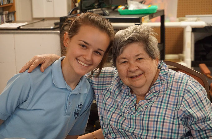 A resident and staff member smiling together in the activity room