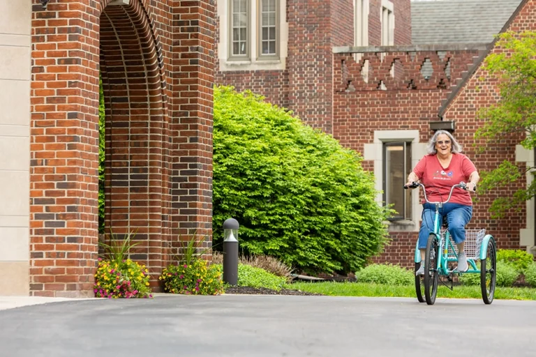 Resident riding a tricycle in the facility's garden area