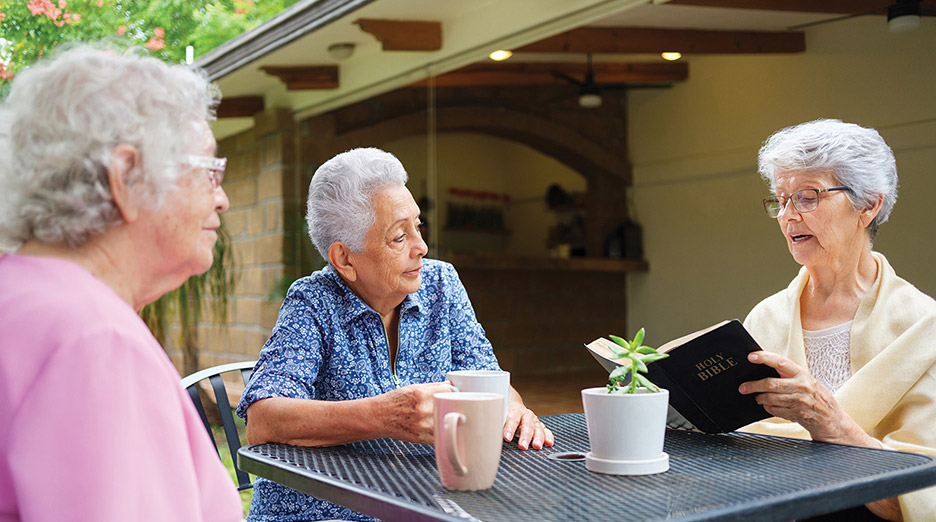 Three residents enjoying a reading activity outdoors