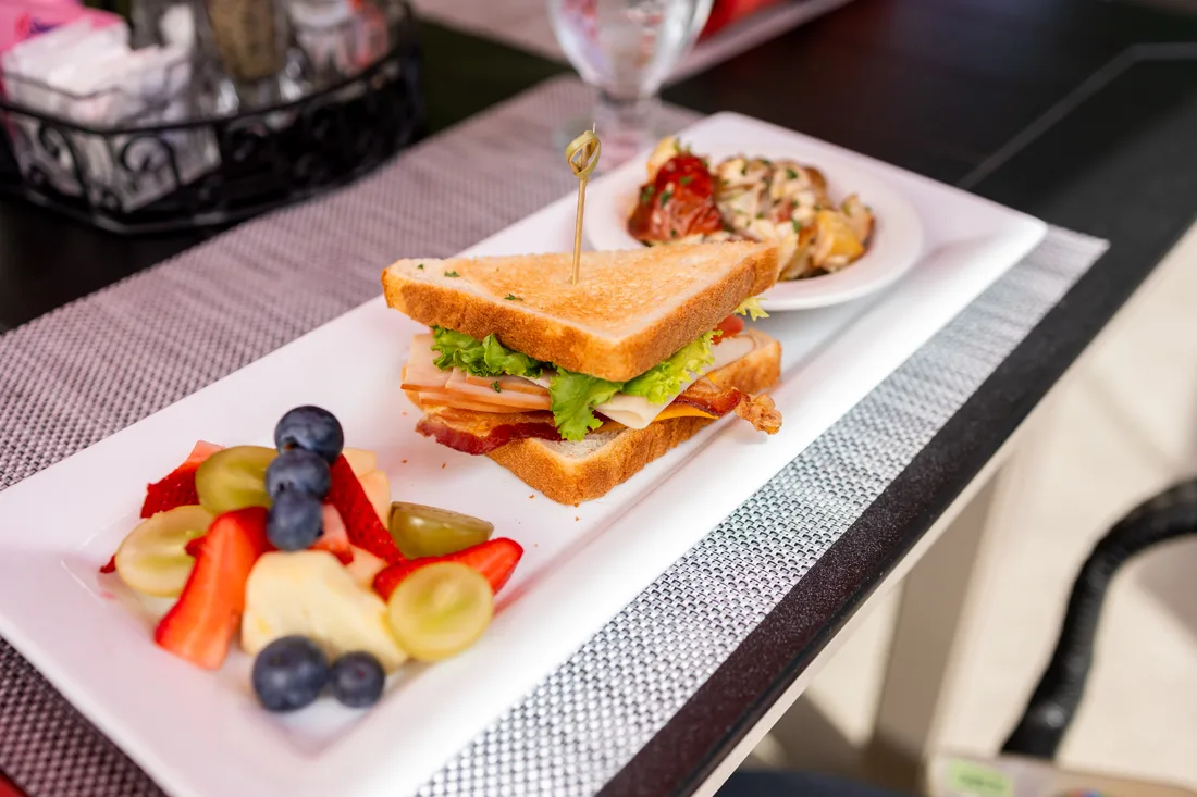 A plate with a sandwich and fruit, likely from a dining area