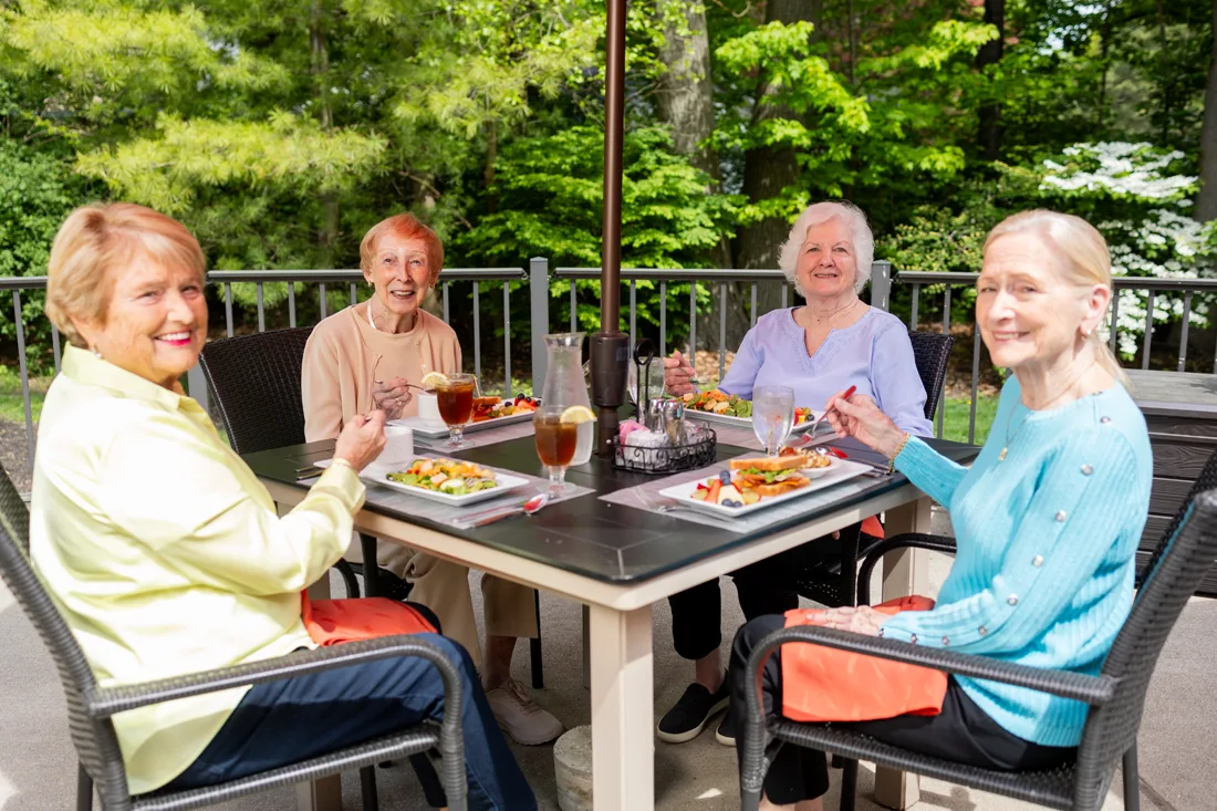 Seniors enjoying a meal outdoors at a dining table