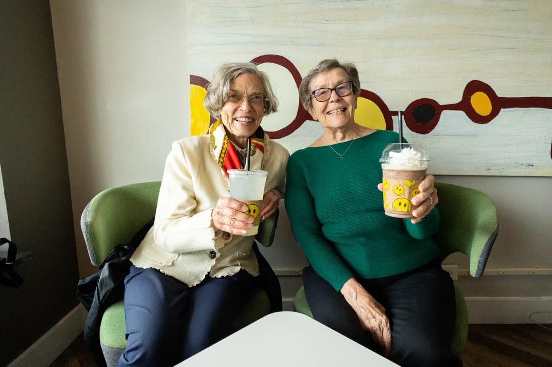 Two residents enjoying beverages in a lounge area