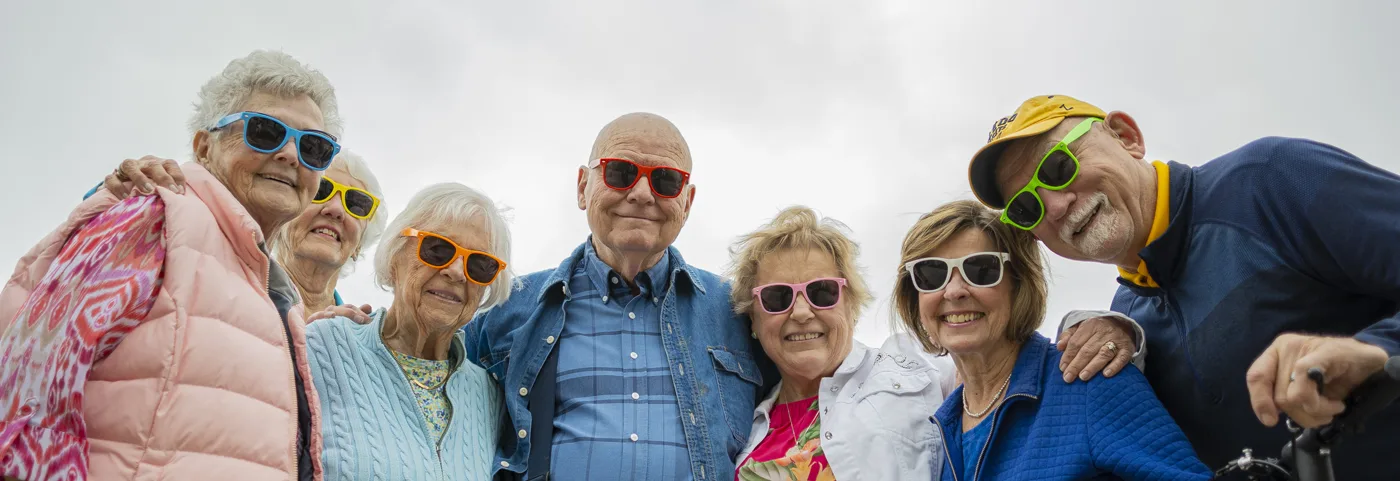 A group of residents smiling outdoors in colorful sunglasses