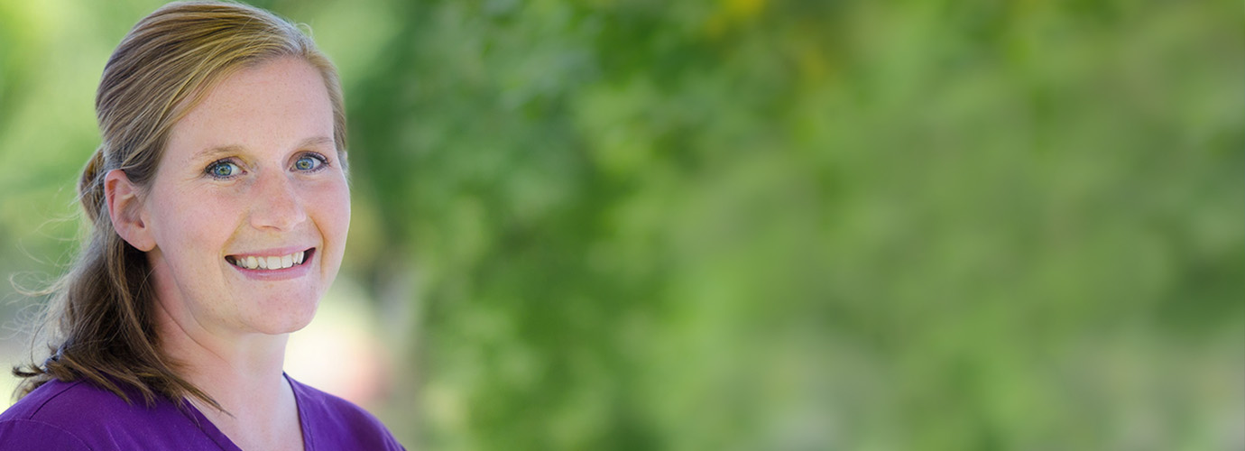 Smiling staff member outdoors in a garden setting