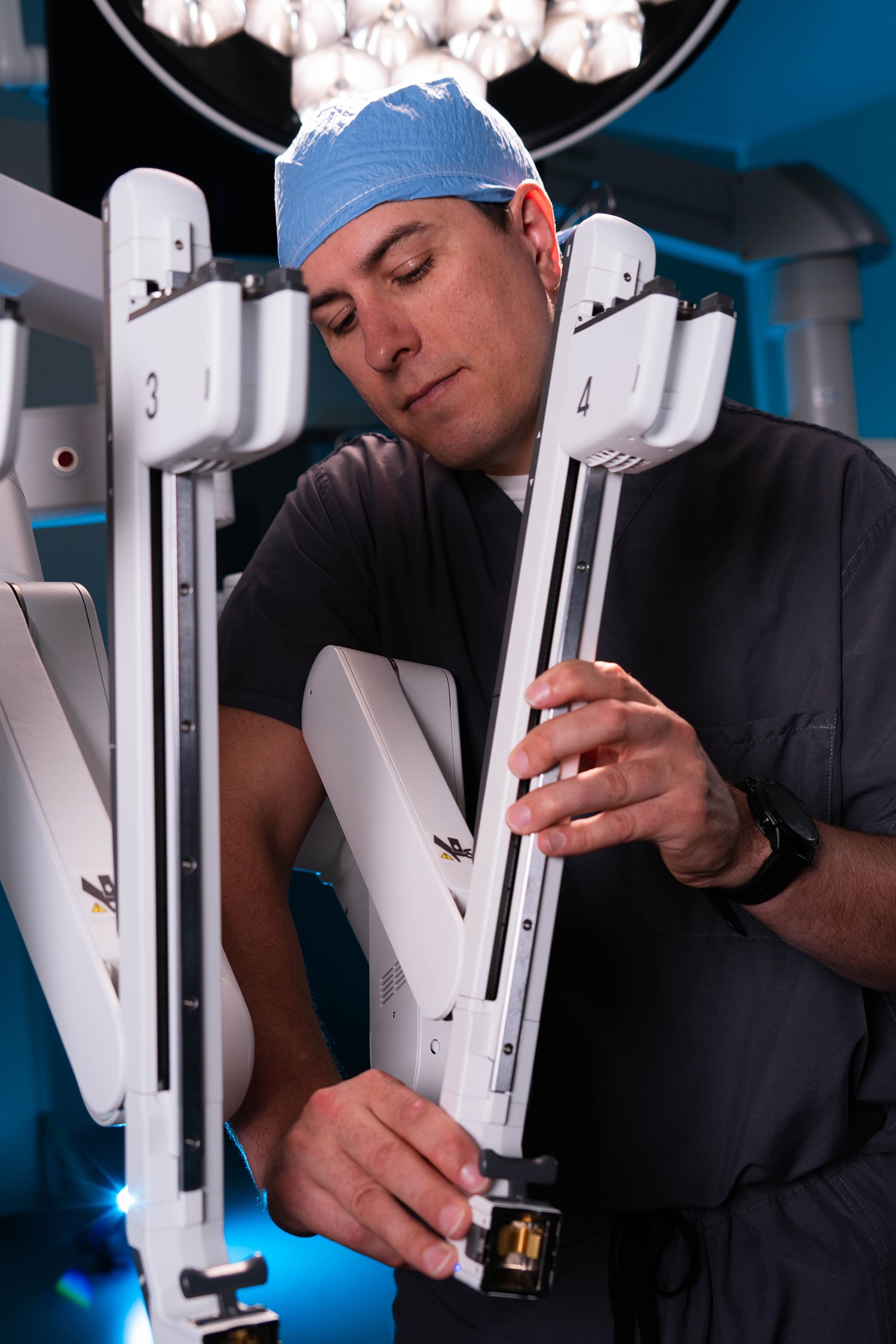 Surgeon adjusting robotic surgical equipment in an operating room