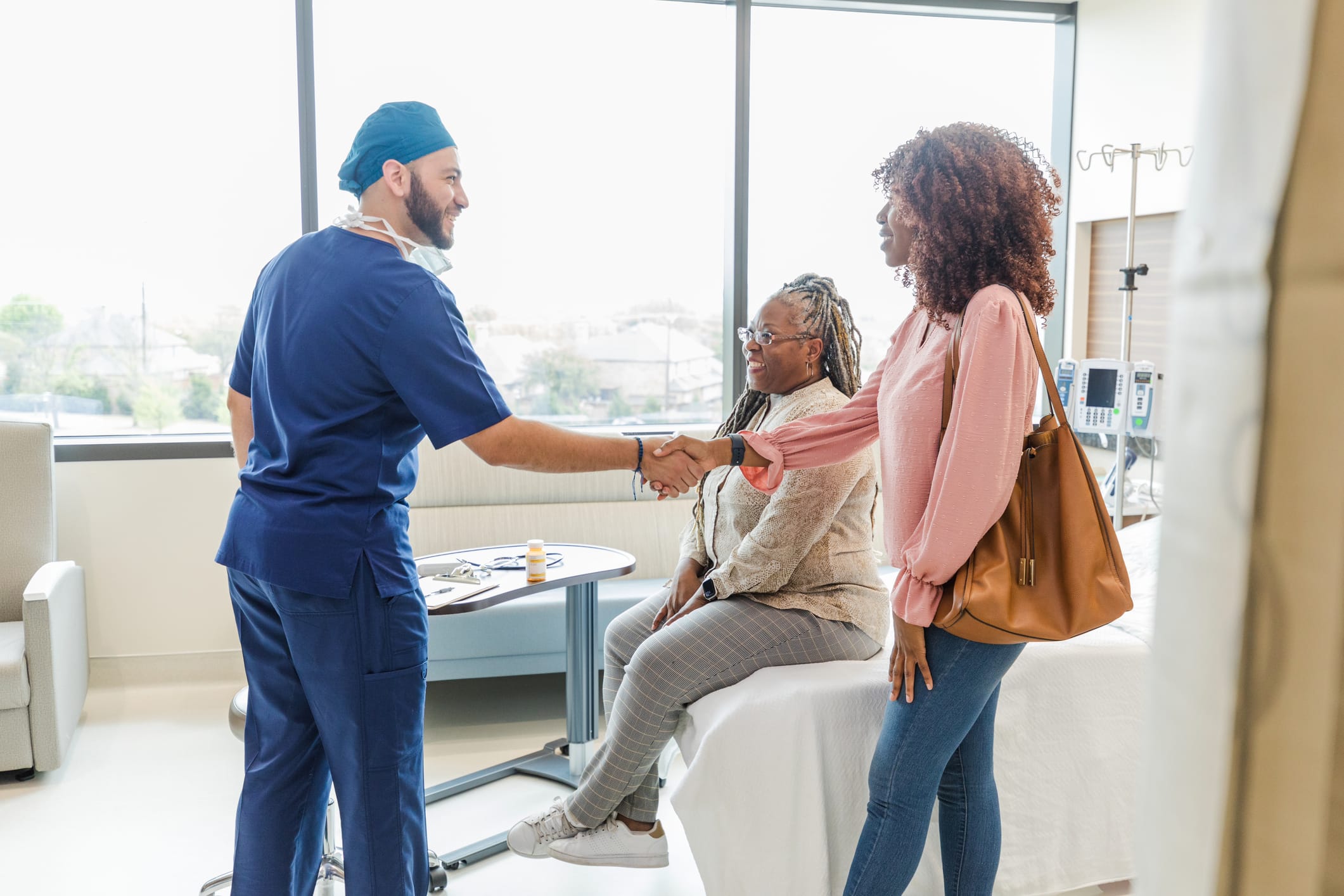 Healthcare professional shaking hands with guests in an interior setting