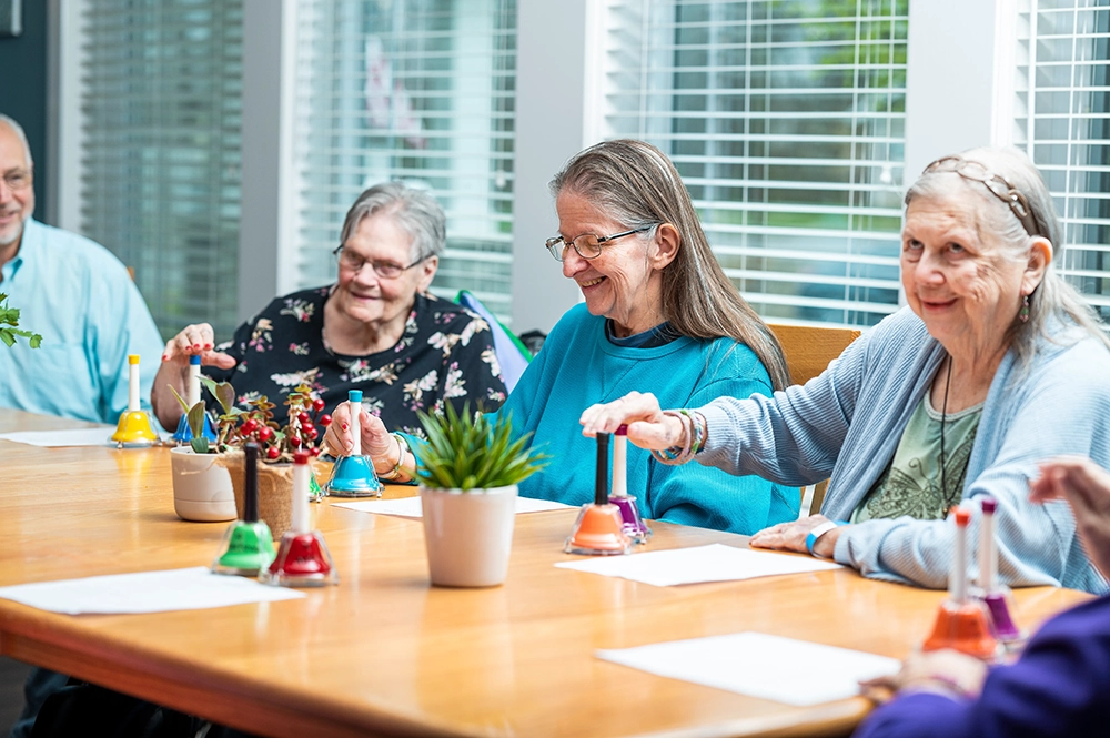 Residents engaged in a bell ringing activity at a communal table