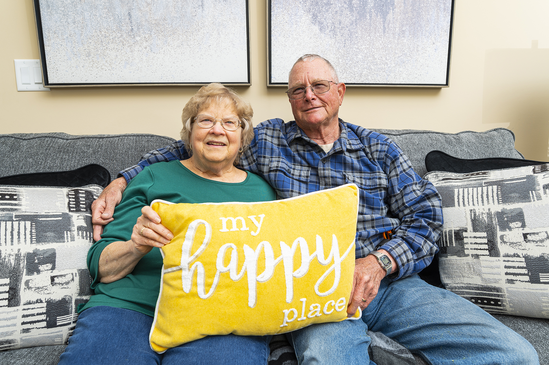 Couple smiling together on a couch with a decorative pillow
