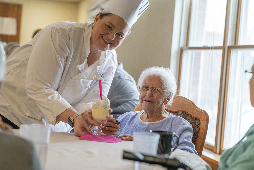Staff member serving dessert to a resident.