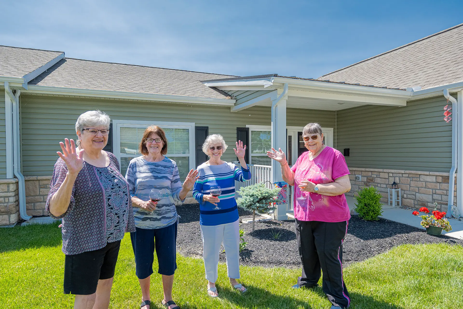 Four residents waving in front of a serene outdoor space