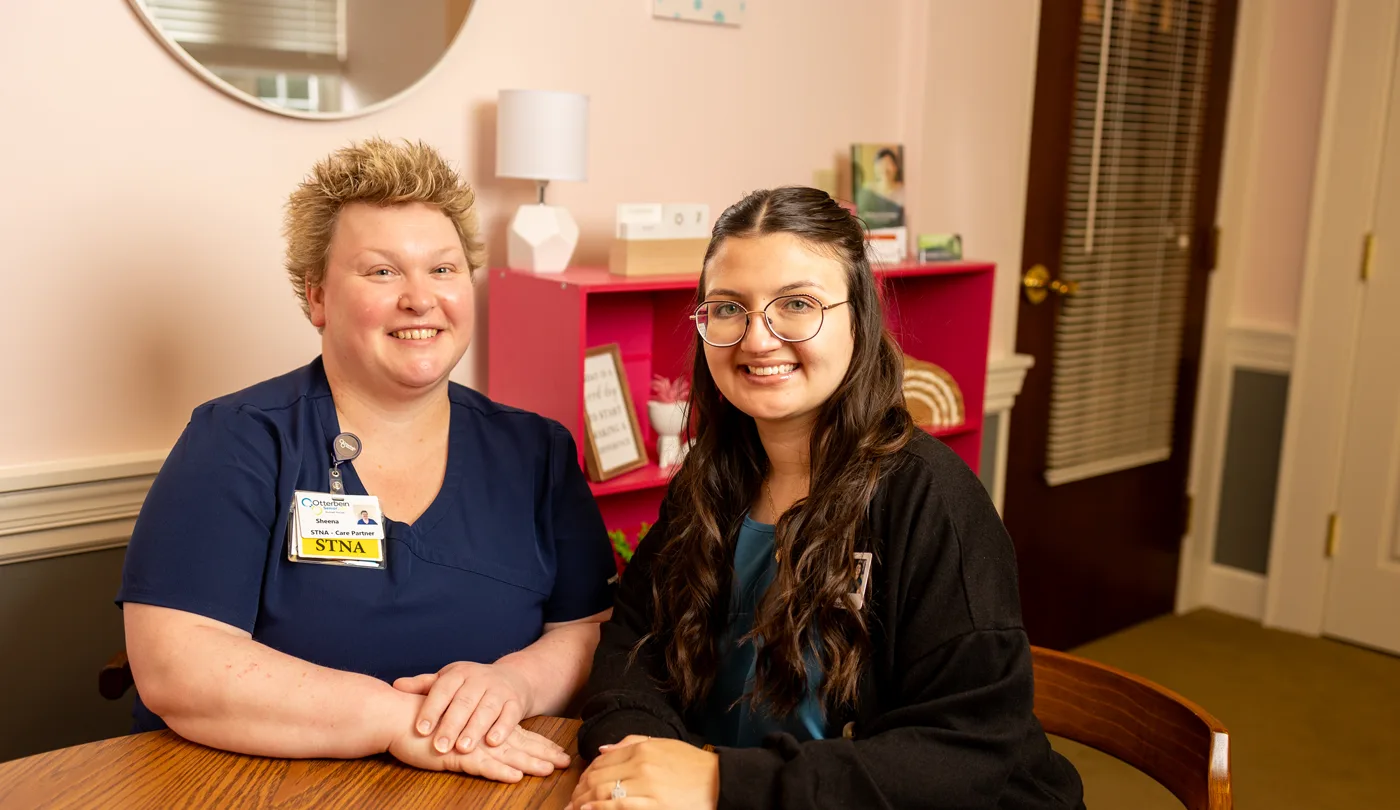 Two smiling staff members in a warm interior setting
