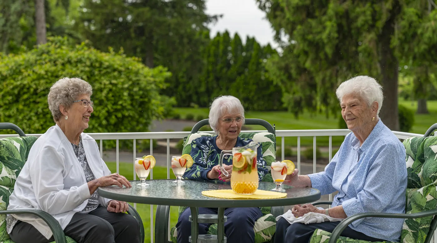 Three women enjoying drinks on an outdoor patio