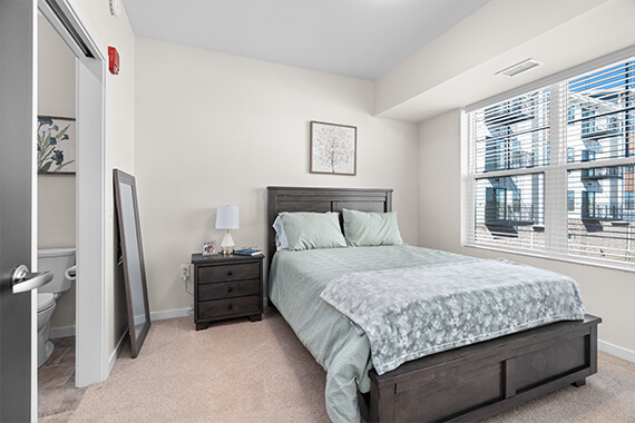Cozy bedroom with a bed, nightstand, and bathroom visible