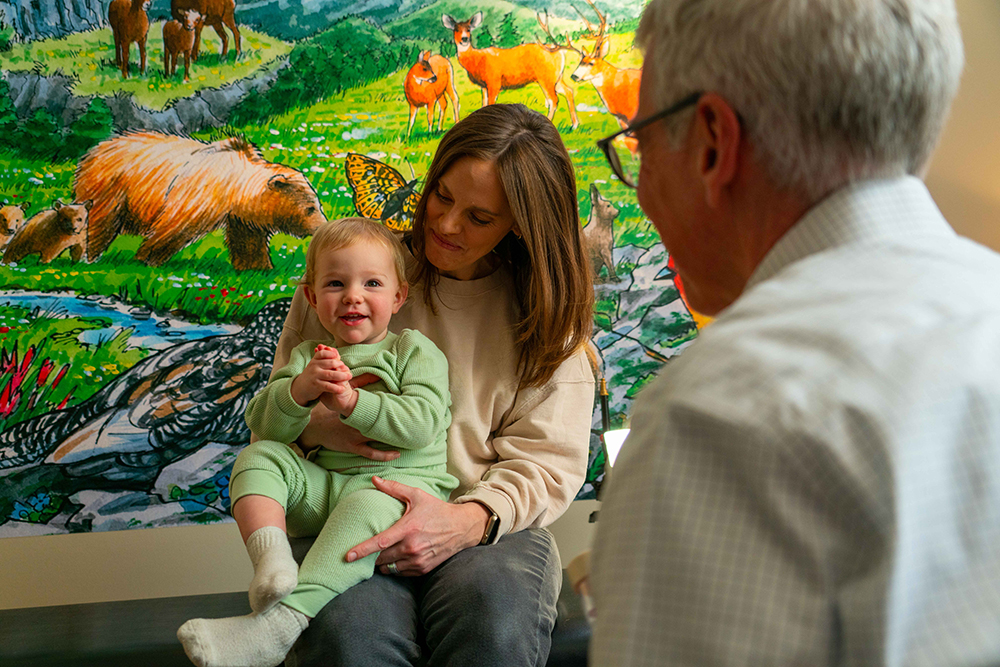 A woman holding a baby smiling at an older man
