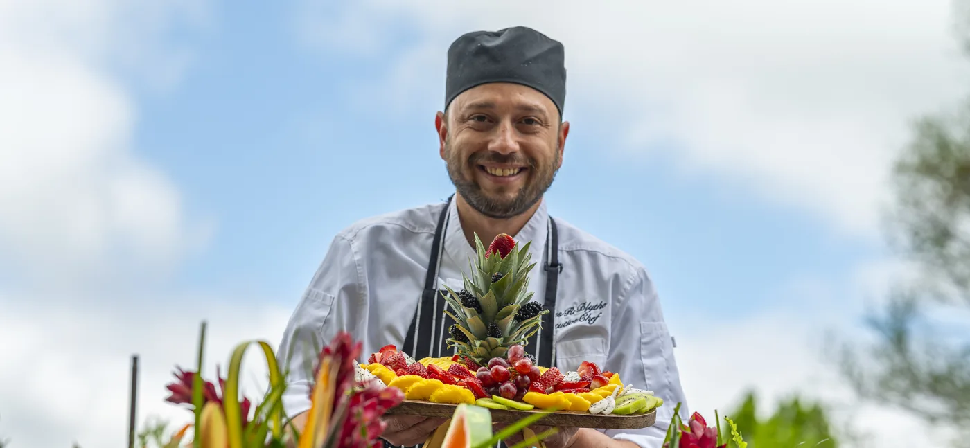Chef presenting a colorful fruit platter in an outdoor setting