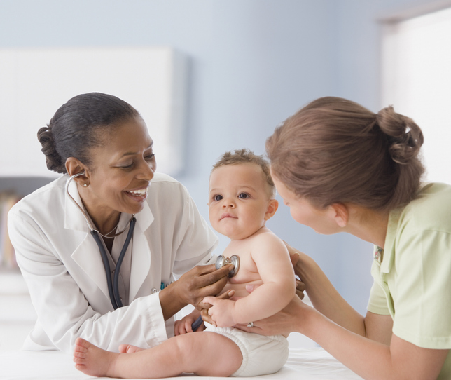 A doctor and nurse examining a baby in a clinical setting.
