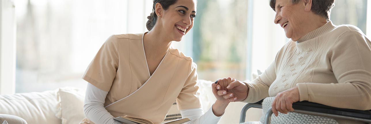 Caregiver holding hands with a resident in a bright room
