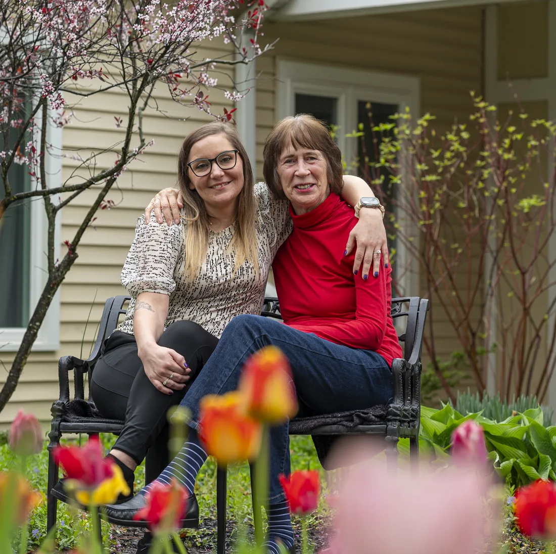 Two women sitting together in a garden with flowers
