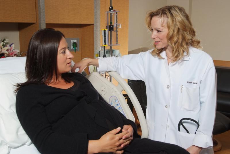 A doctor talking to a pregnant woman in a hospital room