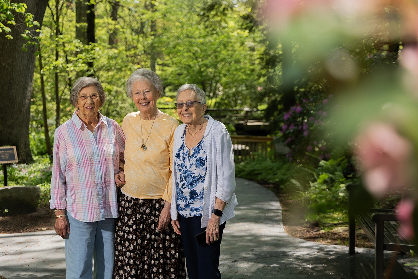 Three seniors smiling in a garden setting