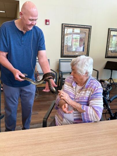 Staff member shows a snake to a resident indoors