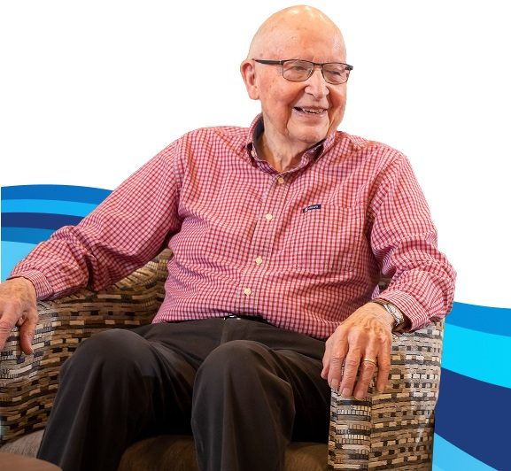 A smiling elderly man sitting in a chair