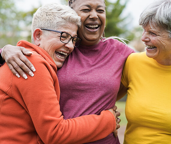 Three residents joyfully embracing outdoors