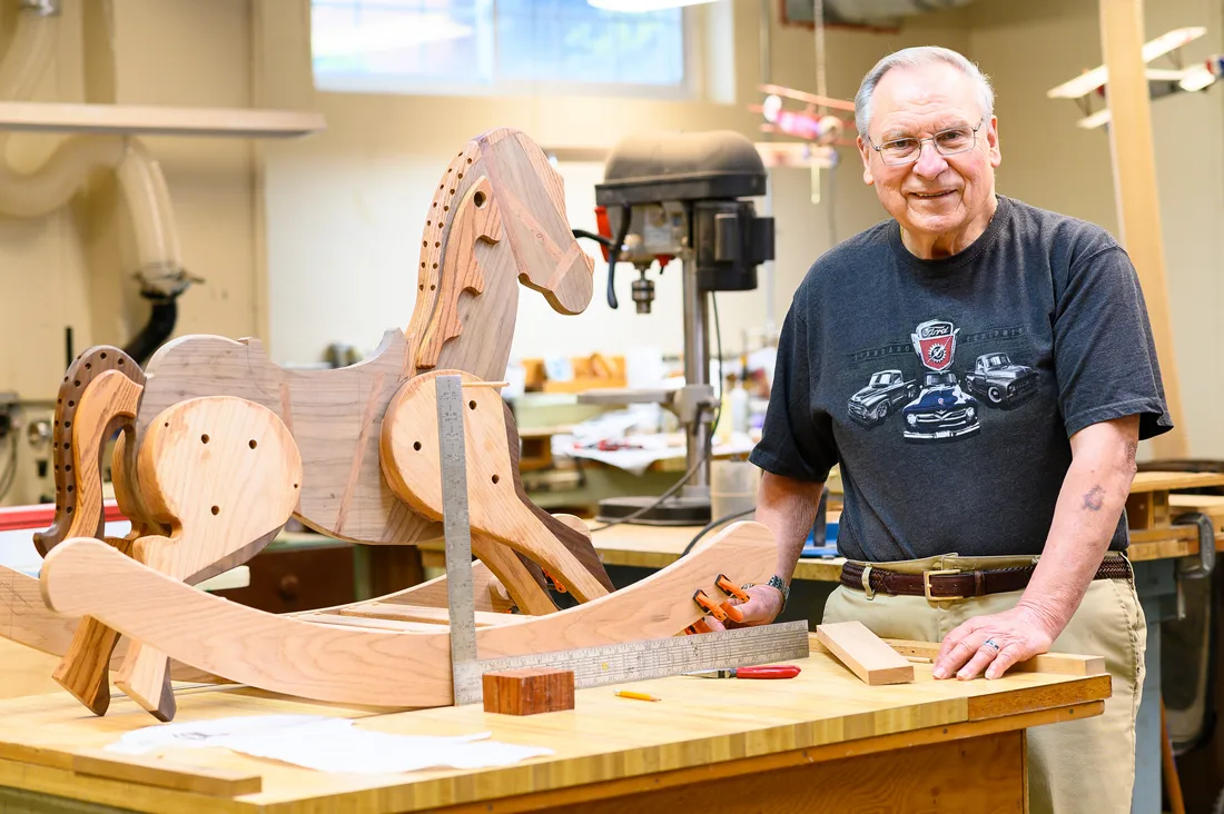 Resident working on a wooden rocking horse in a craft room