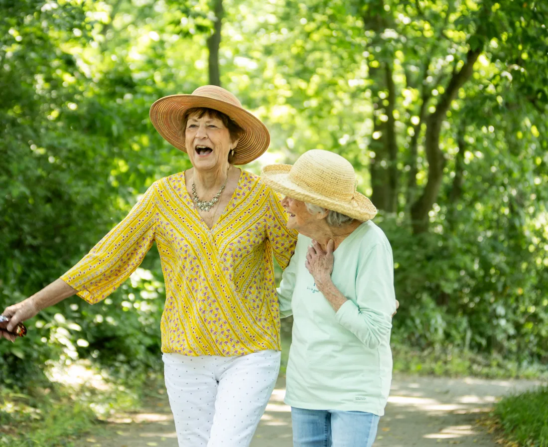 Two women walking in a lush green outdoor path