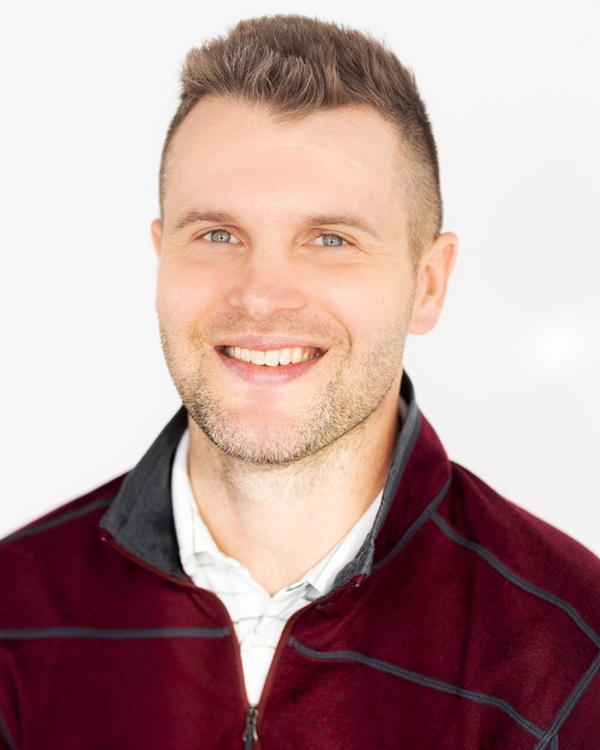 A smiling young man in a maroon jacket