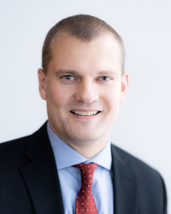 A person in a suit with a neutral background