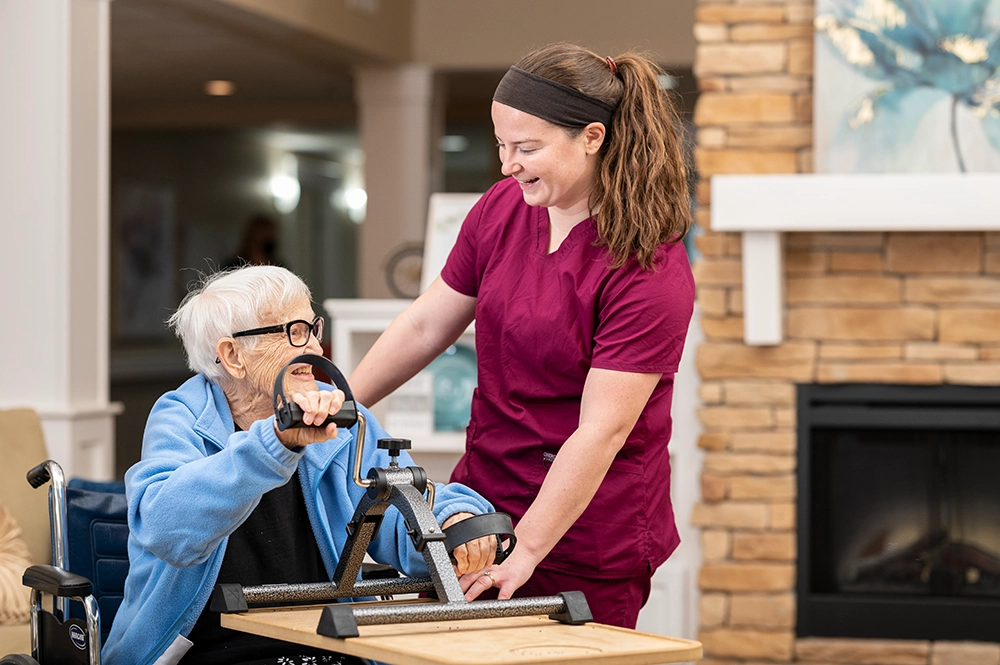 Staff assisting an elderly resident with therapy equipment