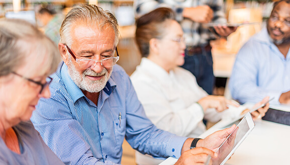Residents engaged with tablets in a communal space