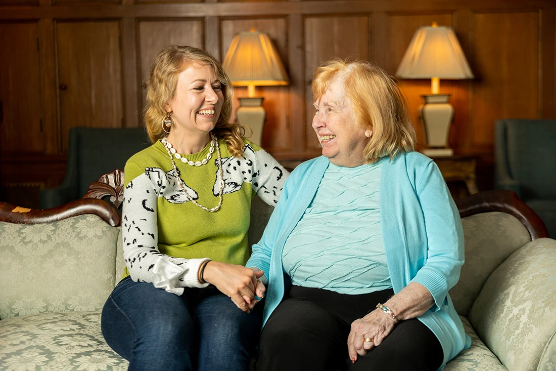 Two women sharing a joyful moment in a cozy lounge