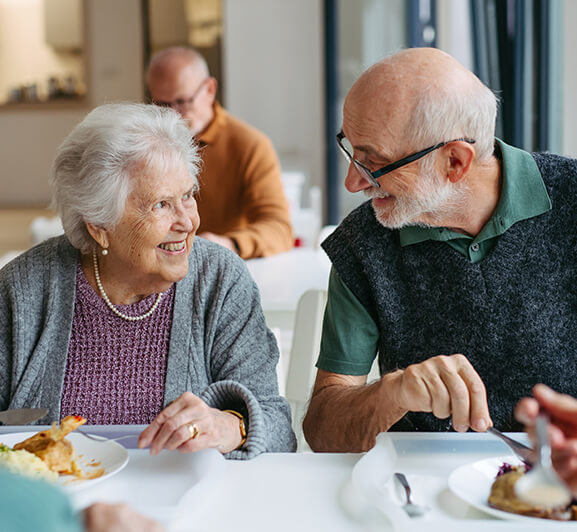 Residents enjoying a meal and conversation in the dining area