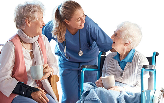 Two residents enjoying coffee while chatting with a nurse