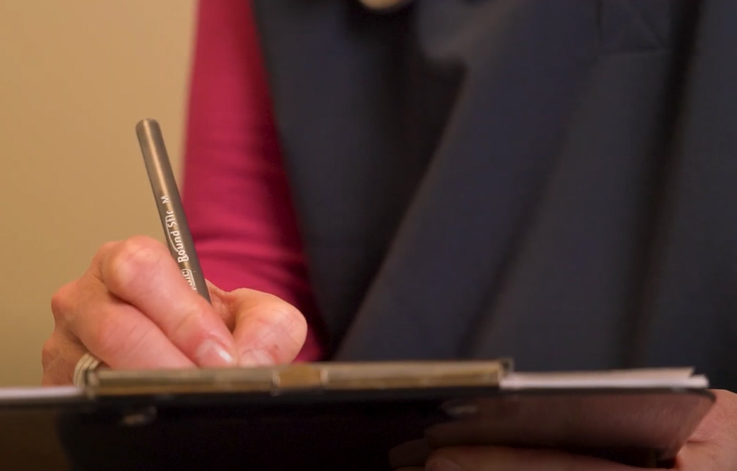 A staff member writing on a clipboard