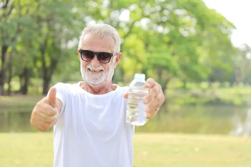 Senior man outdoors giving thumbs up with water bottle