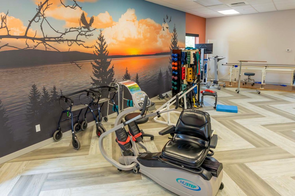 Therapy room with exercise equipment and sunset mural.