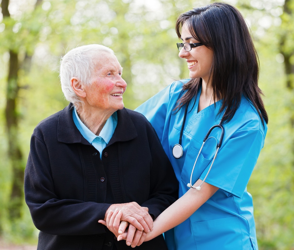 A nurse smiling with an elderly resident outdoors.