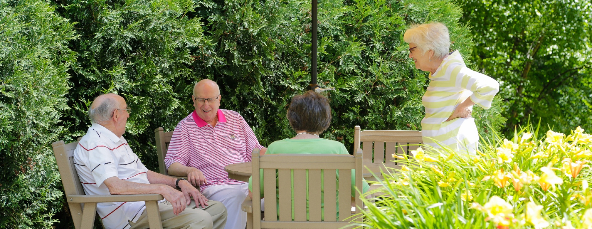 Seniors socializing in a garden seating area.