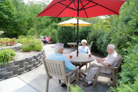 Seniors enjoying conversation under umbrellas in a garden