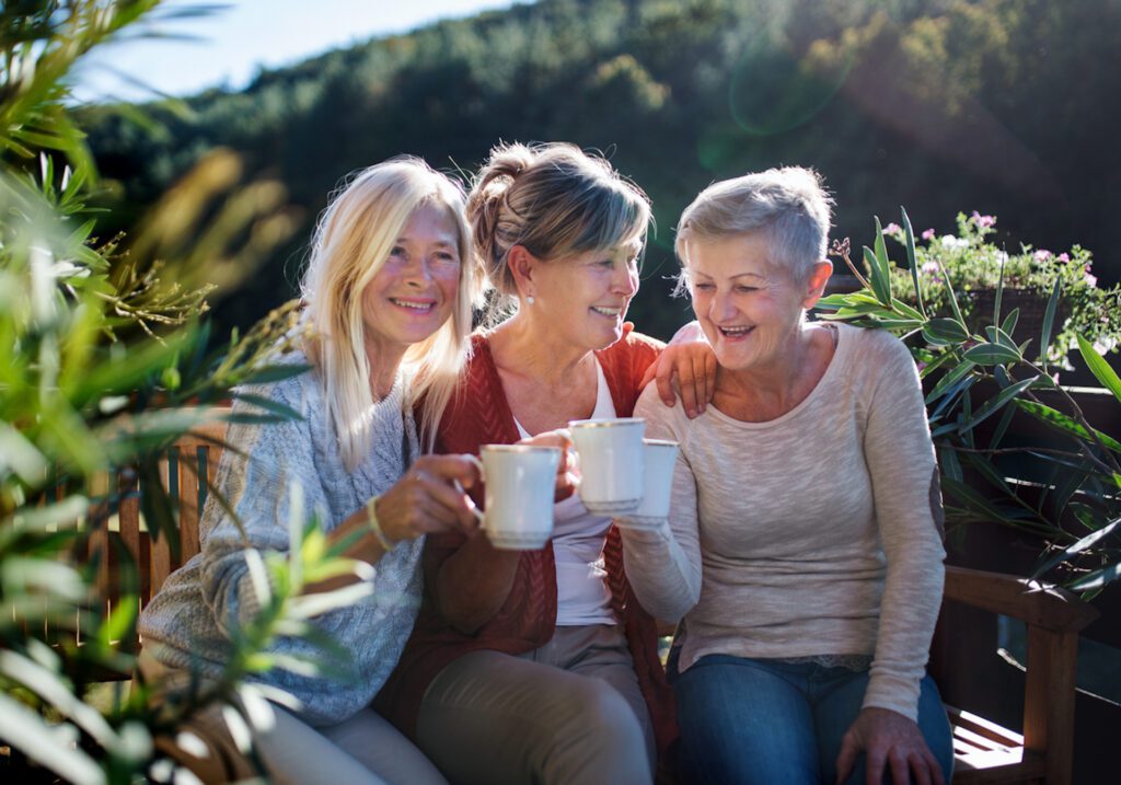 Three women enjoying tea in a garden setting.