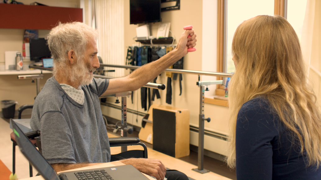 Resident engaging in therapy with staff assistance.