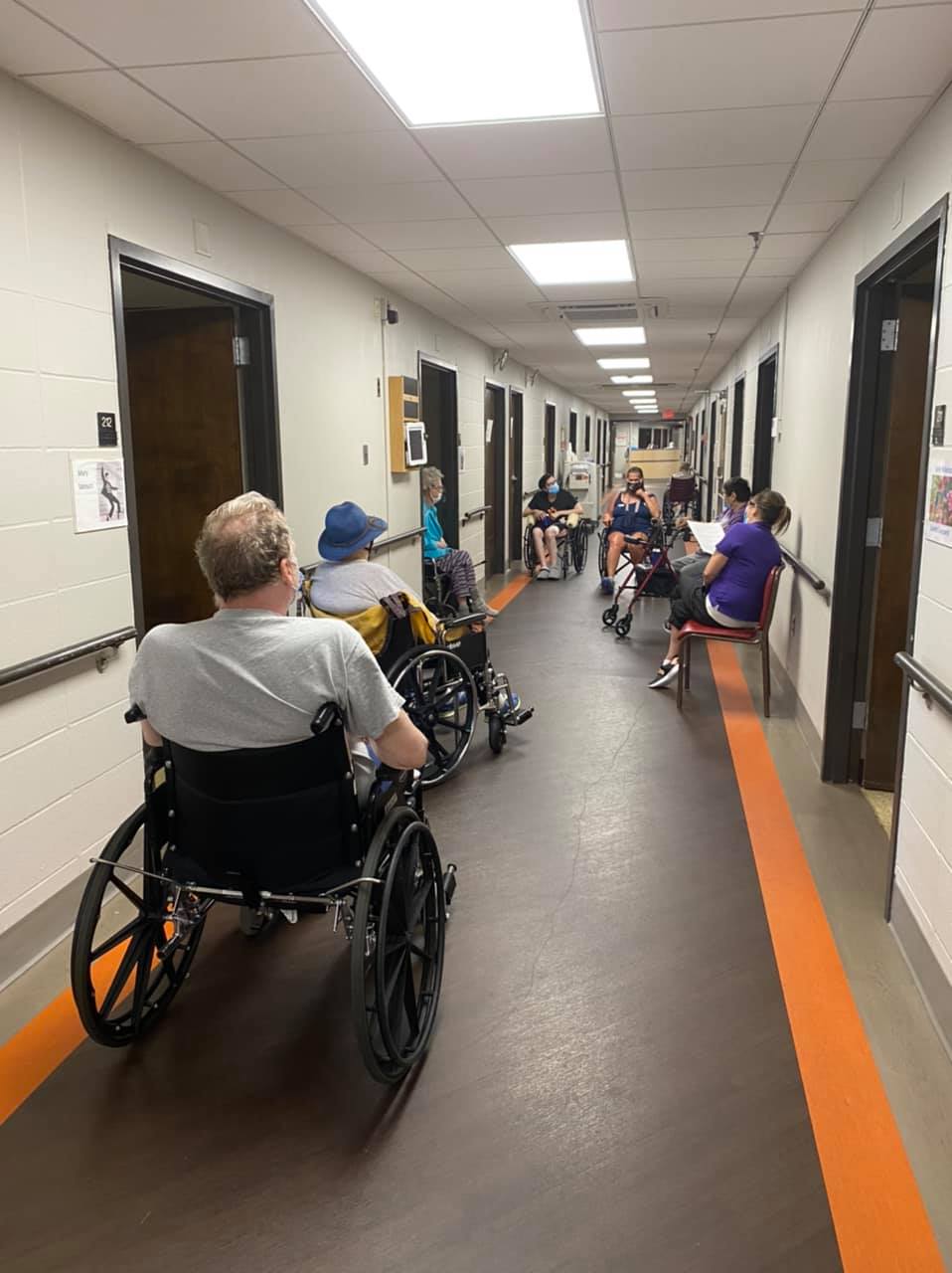 Residents seated in a hallway with wheelchairs