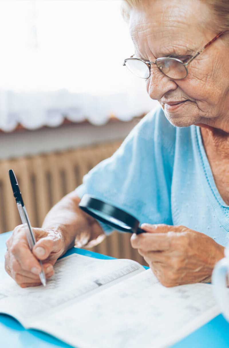 Senior woman engaging in an activity with a magnifying glass.
