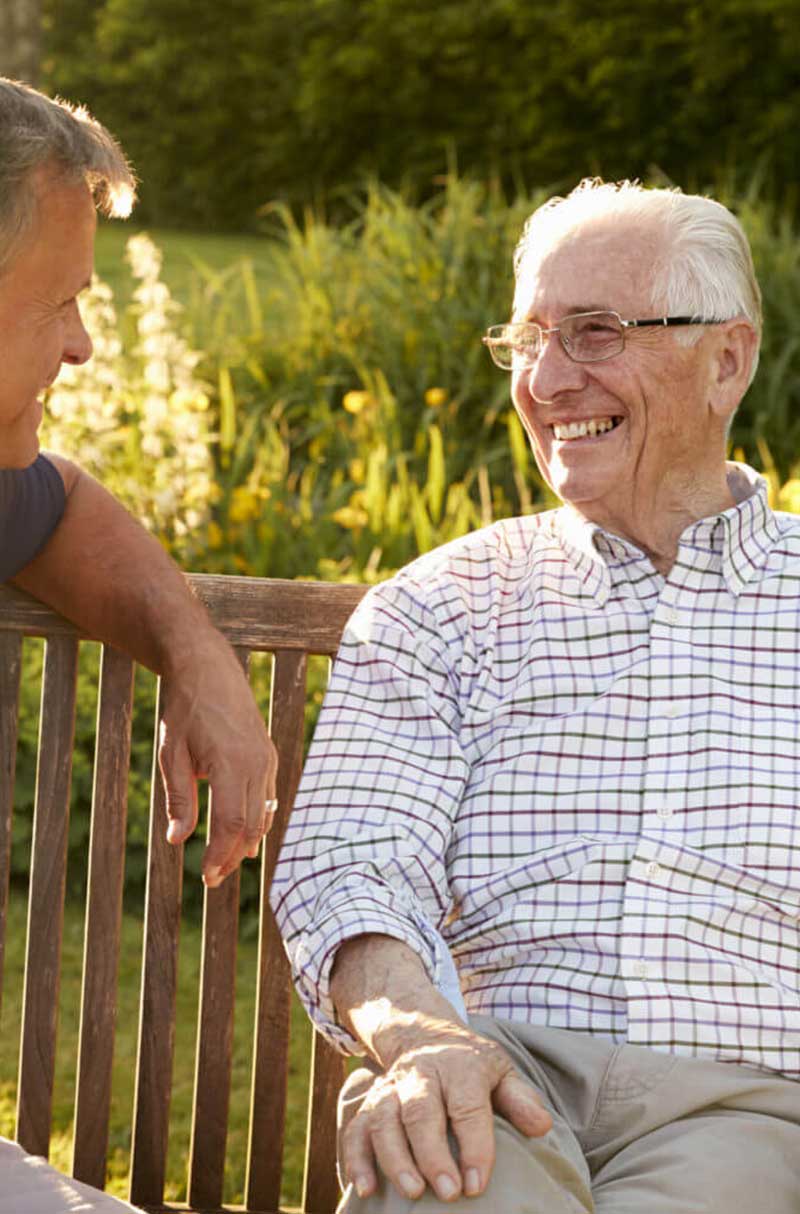 Older man smiling while sitting on a bench