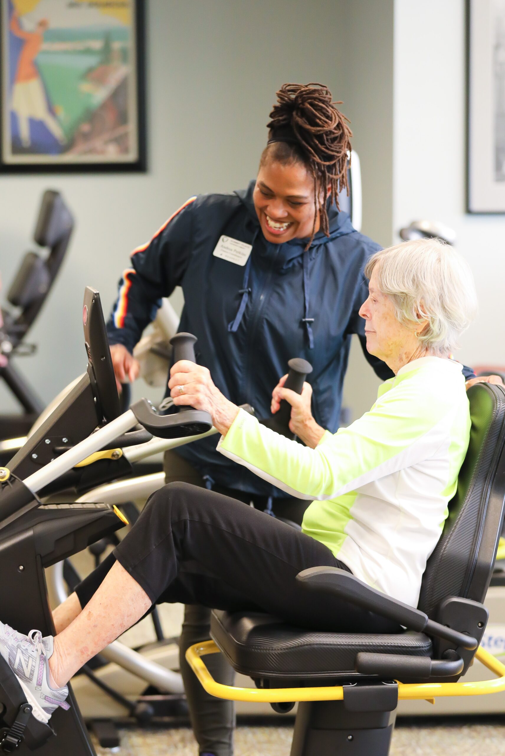 Staff assisting a resident at a fitness station.