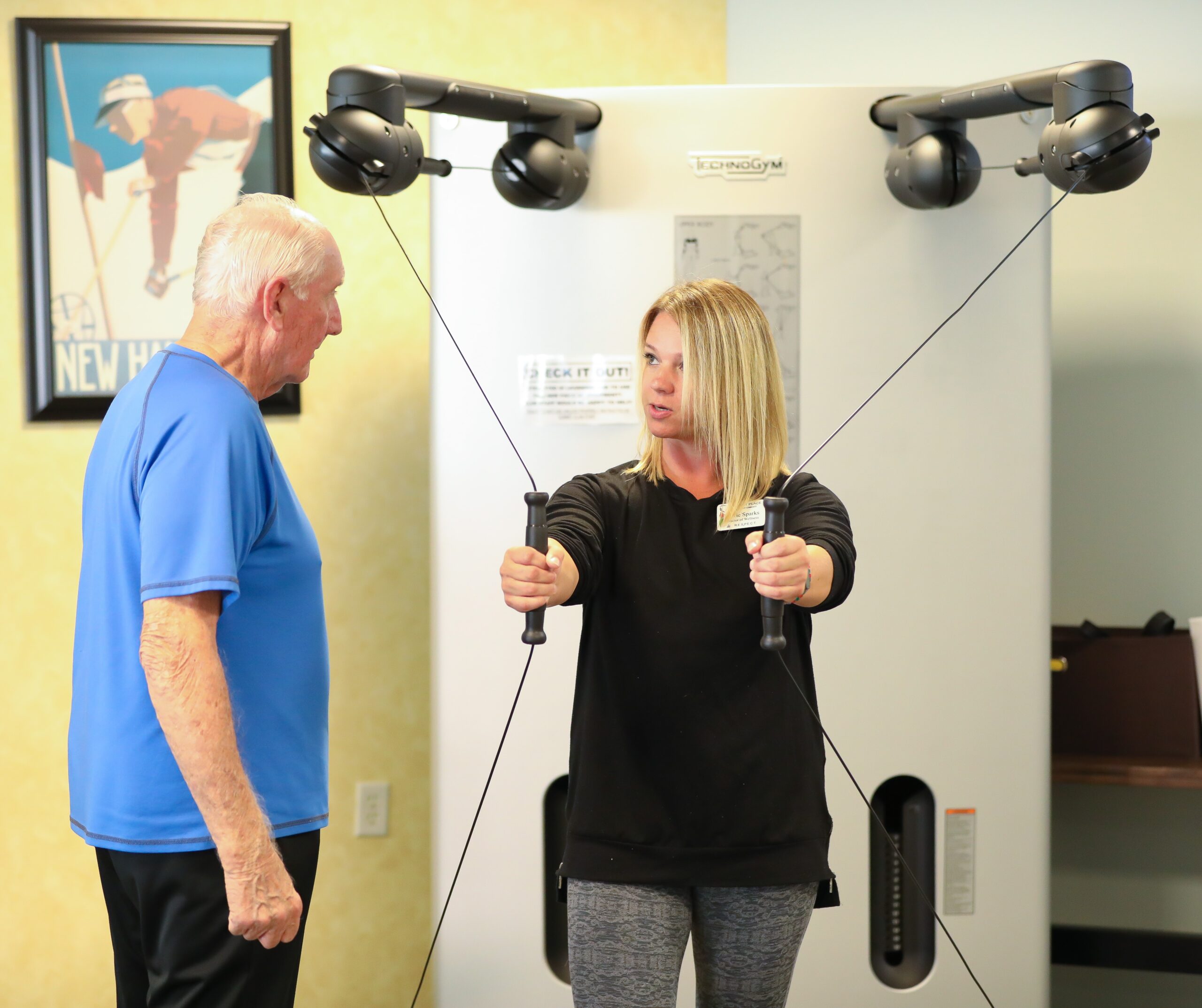 Staff assisting a resident with exercise equipment.