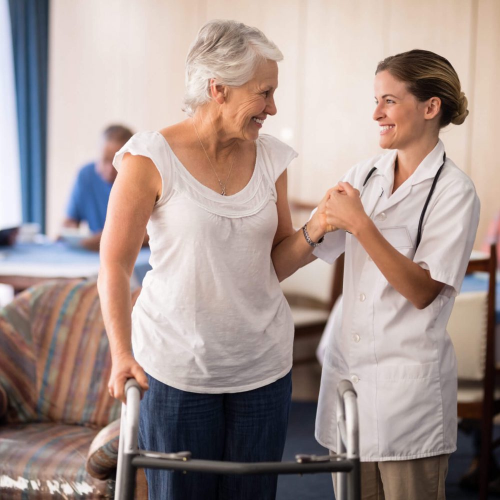 Staff assisting a resident indoors with a walker.